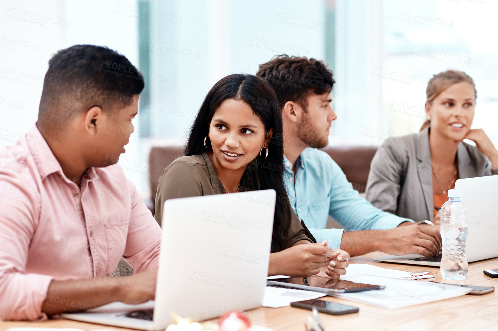 Buy stock photo Cropped shot of a group of young business colleagues sitting in a row at a table in the boardroom