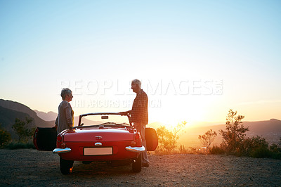Buy stock photo Shot of a senior couple enjoying the sunset during a roadtrip