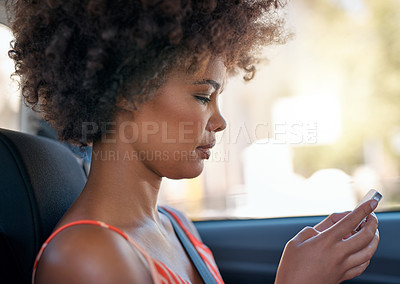 Buy stock photo Cropped shot of an attractive young woman sending a text message while sitting in a car
