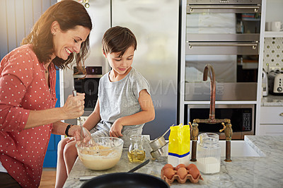 Buy stock photo Shot of a single mother showing her son how to make pancakes