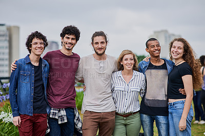 Buy stock photo Portrait of a group of young students standing arms around each other outside in a park during the day