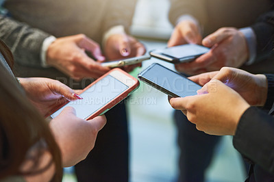 Buy stock photo Cropped shot of a group of unrecognizable businesspeople huddled together using cellphones in an office