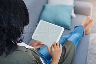 Buy stock photo Shot of an attractive young woman using a digital tablet on the sofa at home