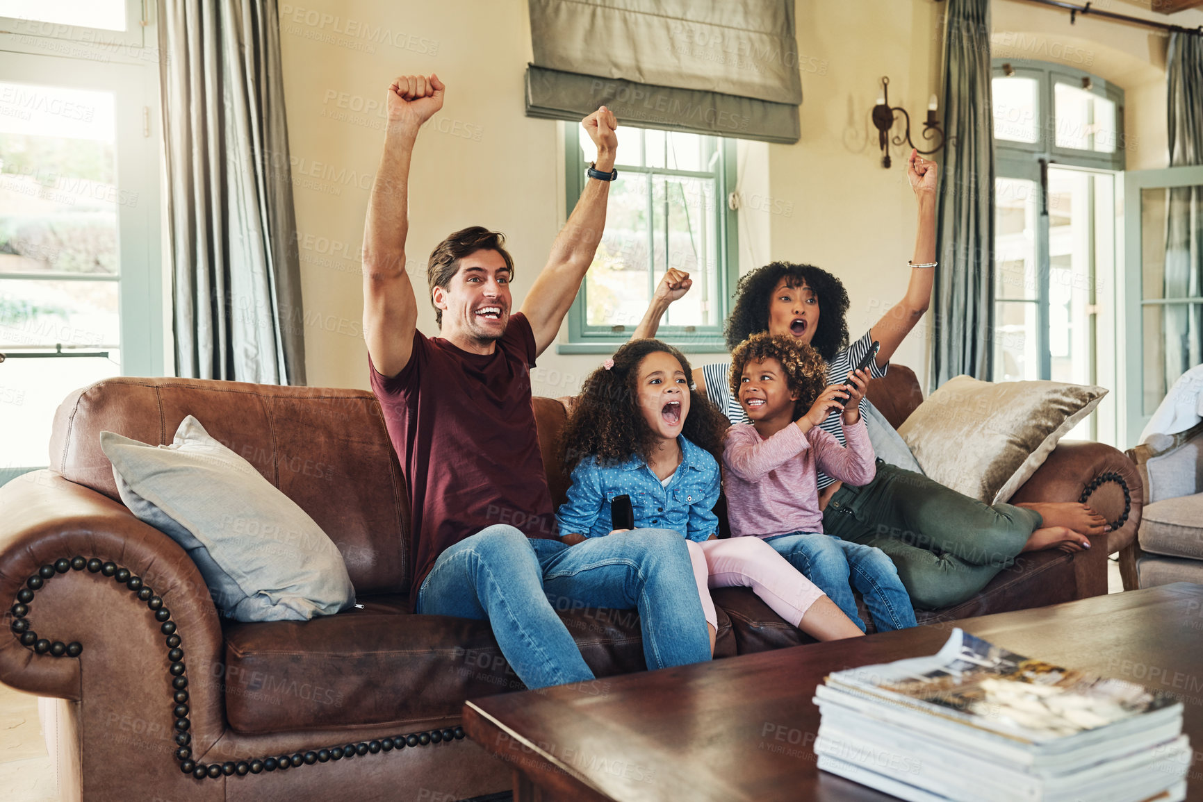 Buy stock photo Shot of a beautiful young family of four celebrating while watching tv together at home