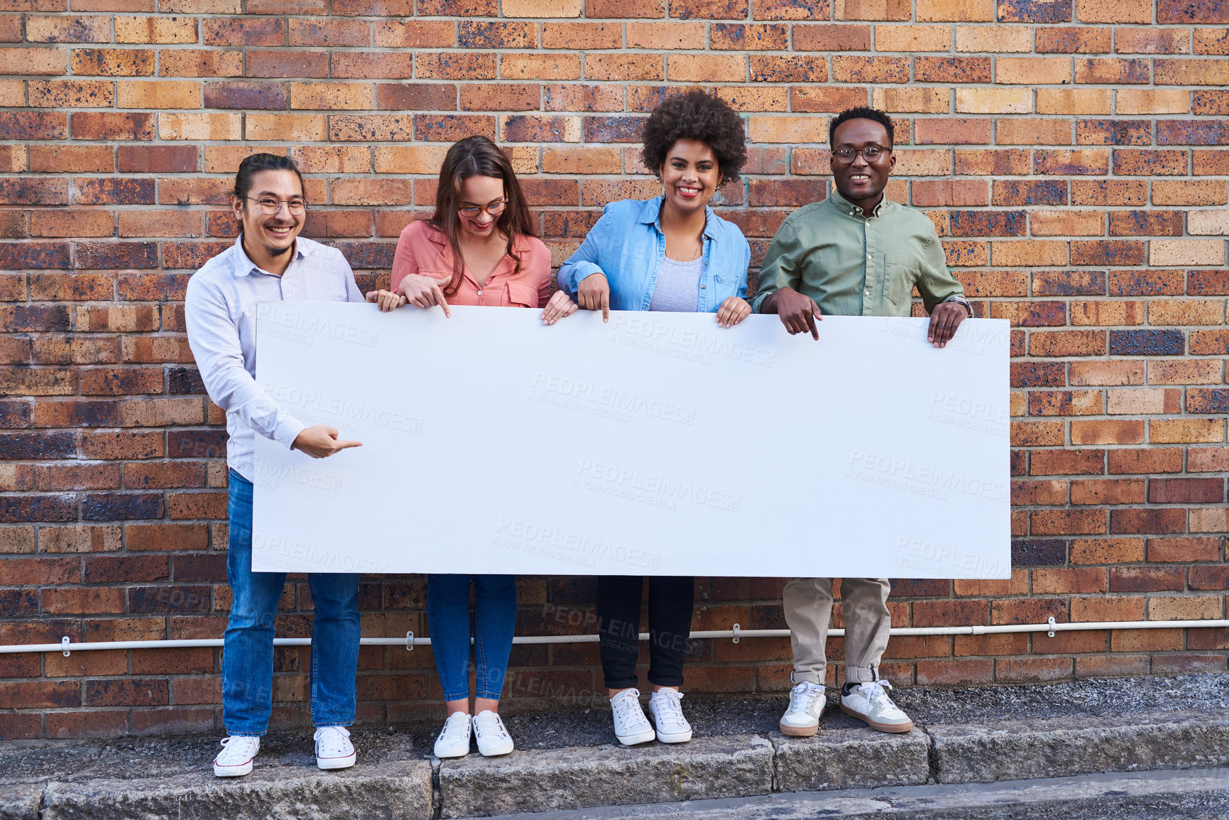 Buy stock photo Shot of a group of young people holding a blank banner against an urban background outdoors