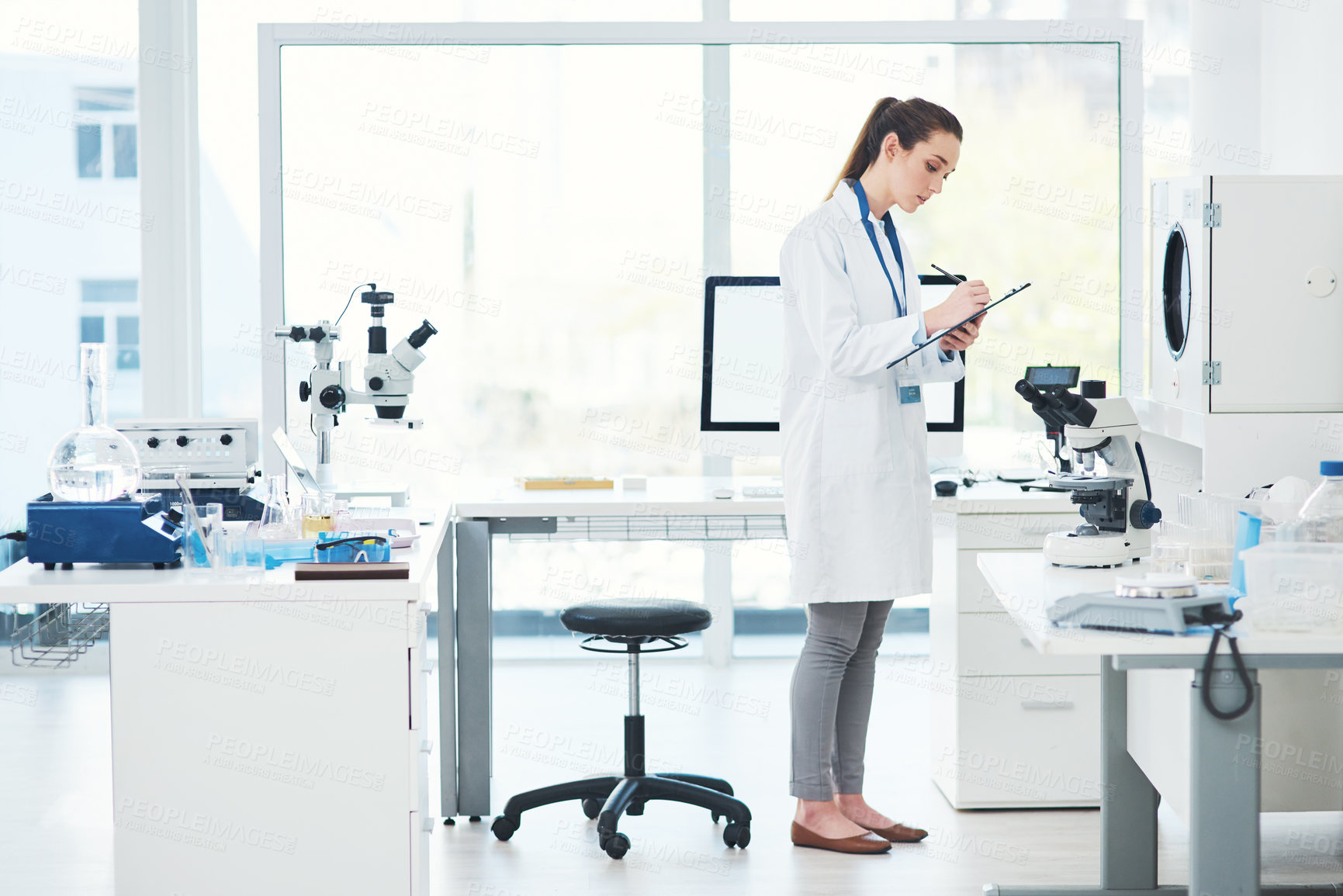 Buy stock photo Cropped shot of a focused young female scientist conducting experiments inside of a laboratory during the day
