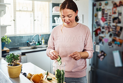 Buy stock photo Cropped shot of a young woman making a smoothie in the kitchen at home