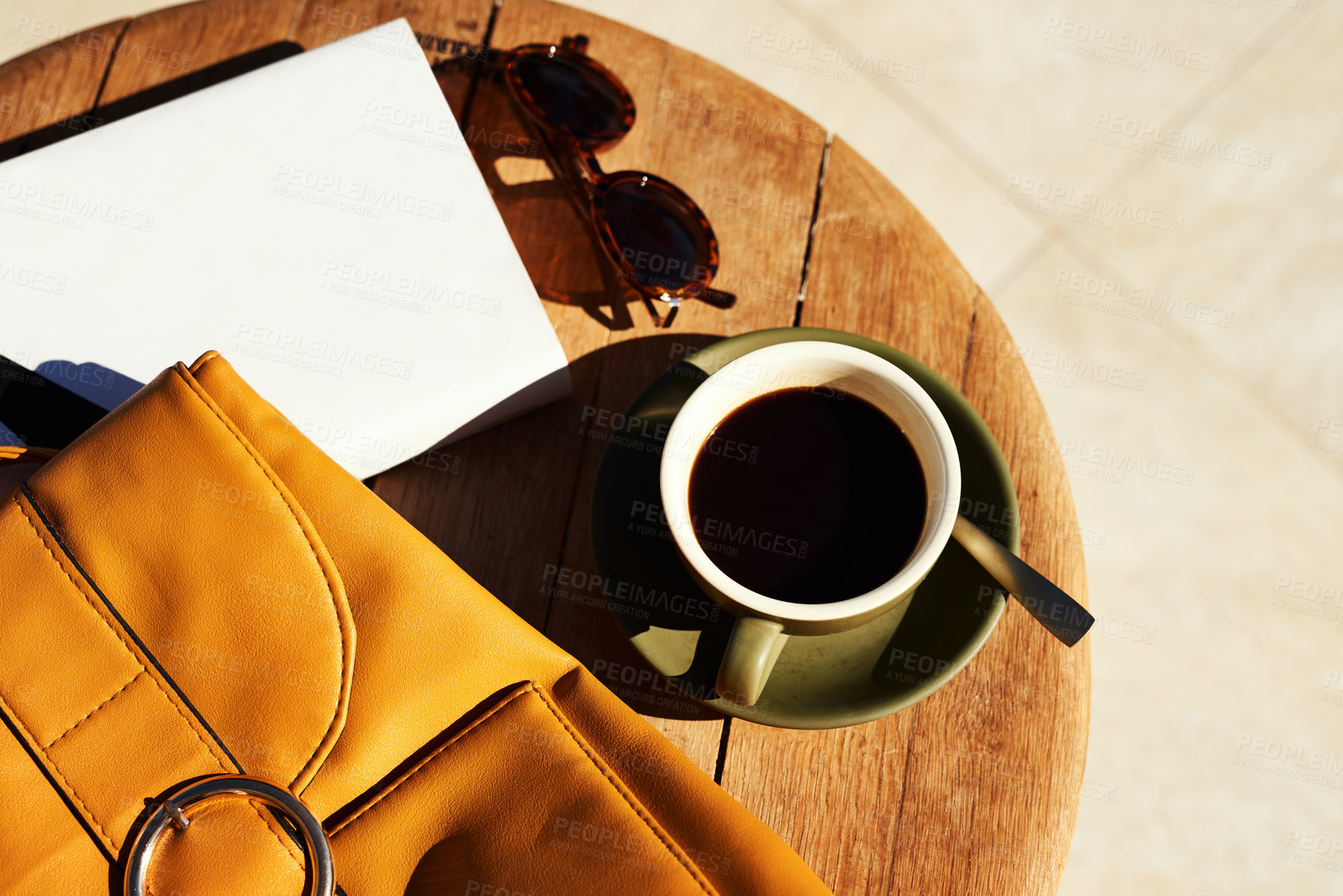 Buy stock photo High angle shot of a cup of coffee and a bag neatly arranged on a coffee table during the day
