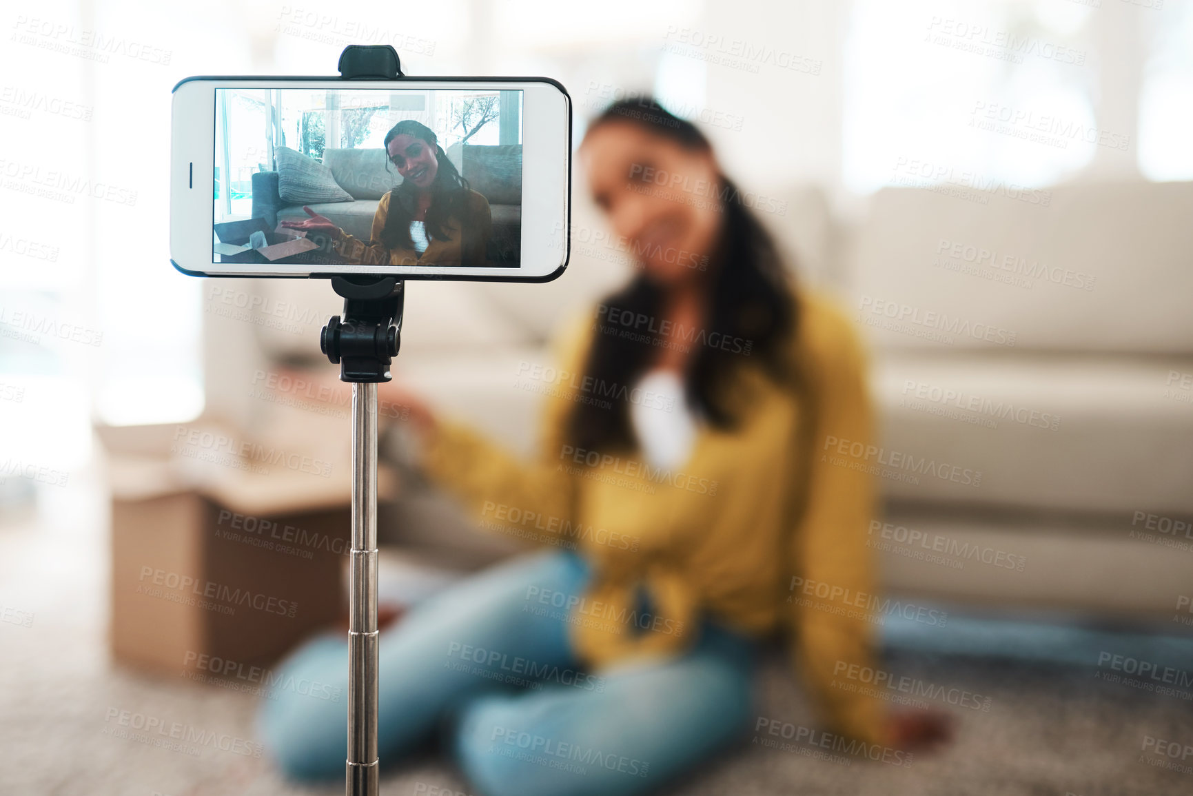 Buy stock photo Cropped shot of an attractive young businesswoman sitting in her living room and using her cellphone to record her vlog