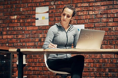 Buy stock photo Cropped shot of a fitness instructor making notes while using a laptop