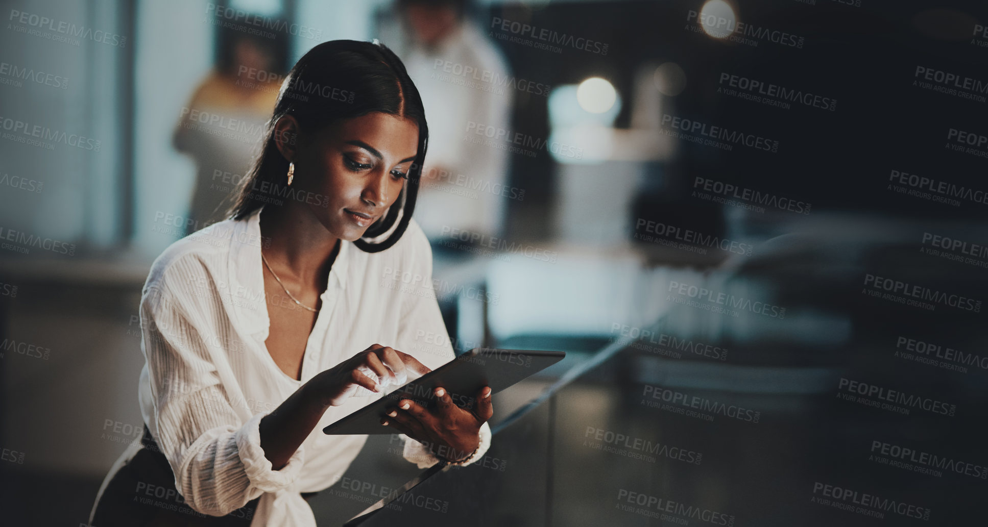 Buy stock photo Shot of a young businesswoman using a digital tablet in an office at night