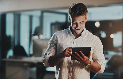 Buy stock photo Shot of a young businessman using a digital tablet in an office at night