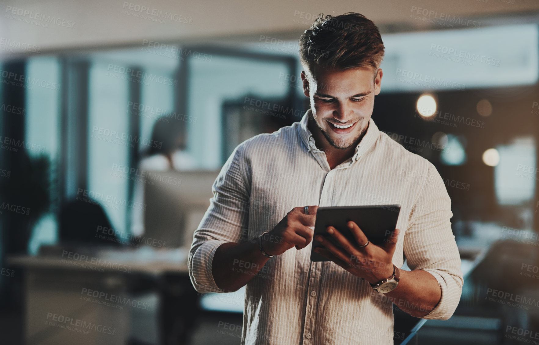 Buy stock photo Shot of a young businessman using a digital tablet in an office at night