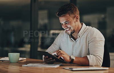 Buy stock photo Shot of a young businessman using a digital tablet in an office at night