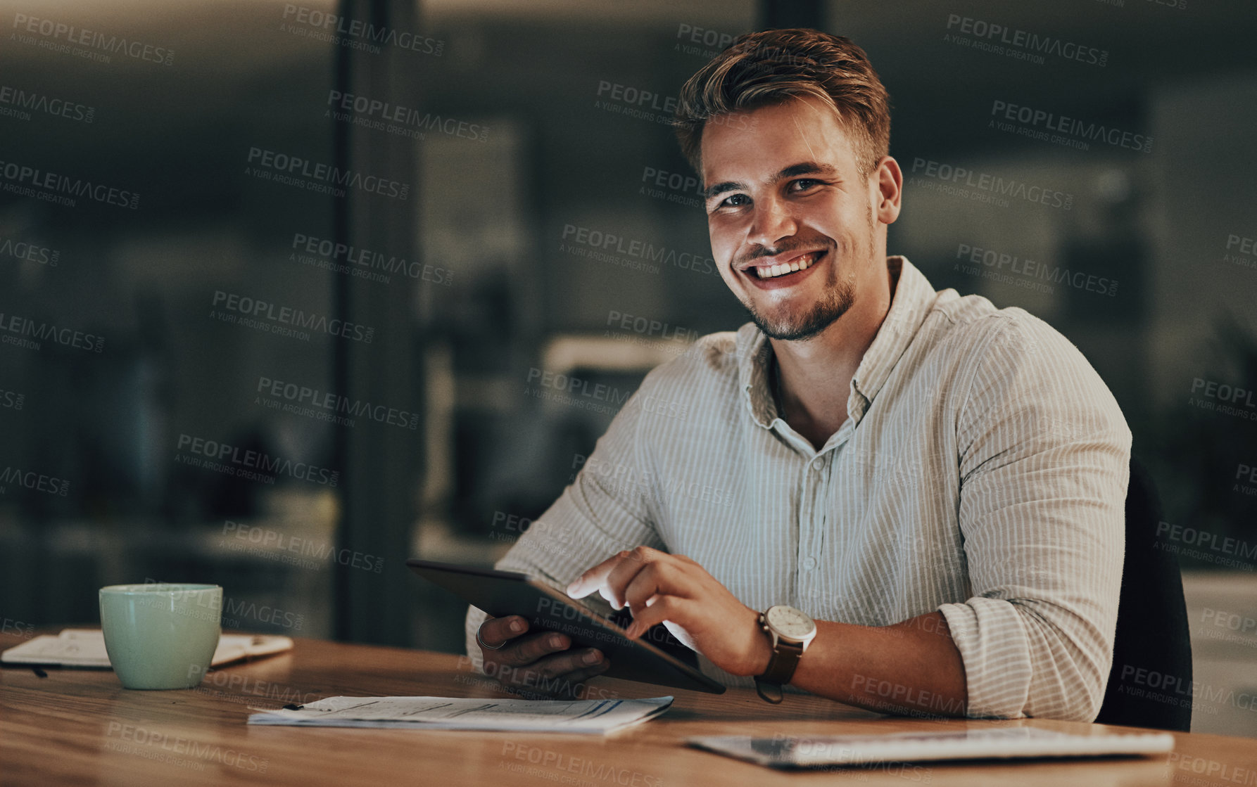 Buy stock photo Portrait of a young businessman using a digital tablet in an office at night