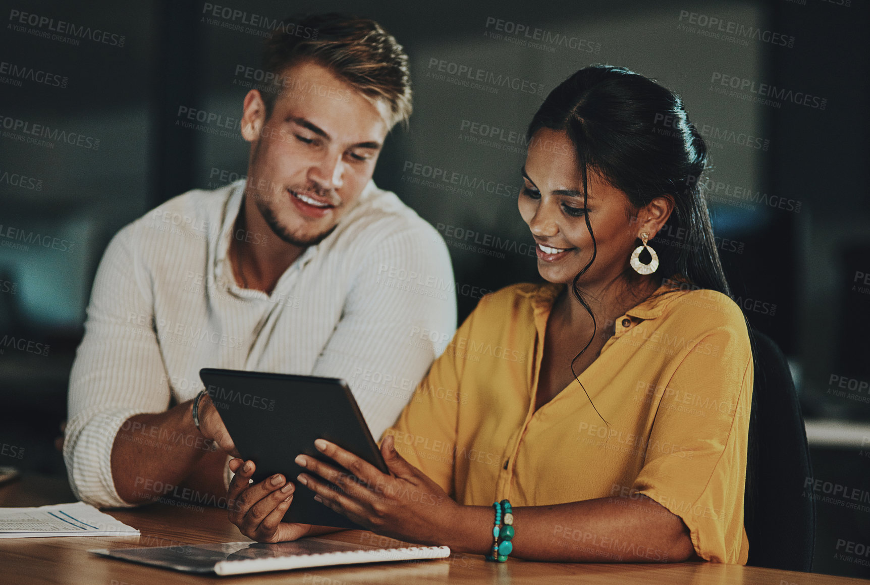 Buy stock photo Shot of two businesspeople using a digital tablet together in an office at night