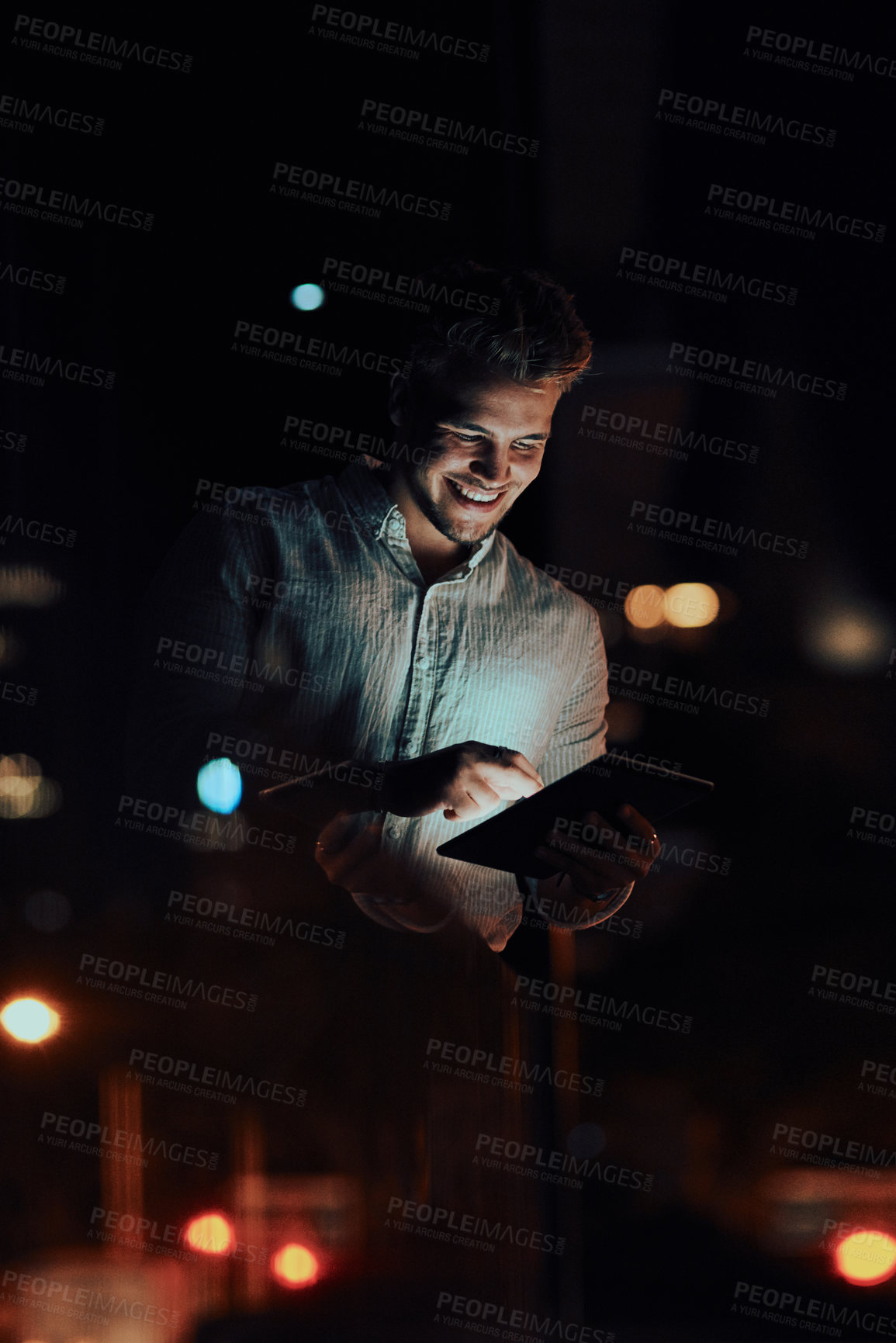 Buy stock photo Shot of a young businessman using a digital tablet outside an office at night