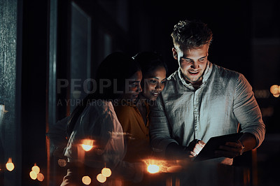 Buy stock photo Shot of a group of businesspeople using a digital tablet together outside an office at night