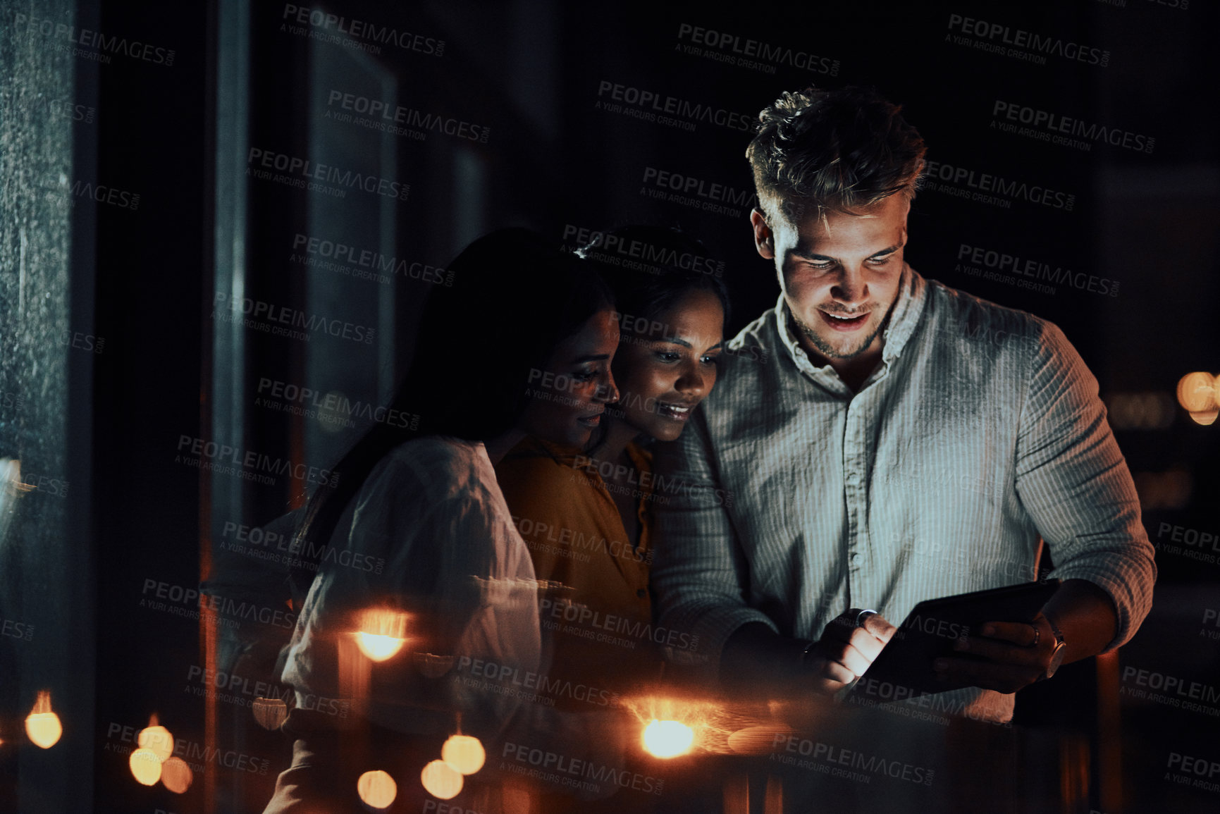 Buy stock photo Shot of a group of businesspeople using a digital tablet together outside an office at night