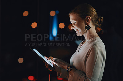 Buy stock photo Shot of a young businesswoman using a digital tablet outside an office at night