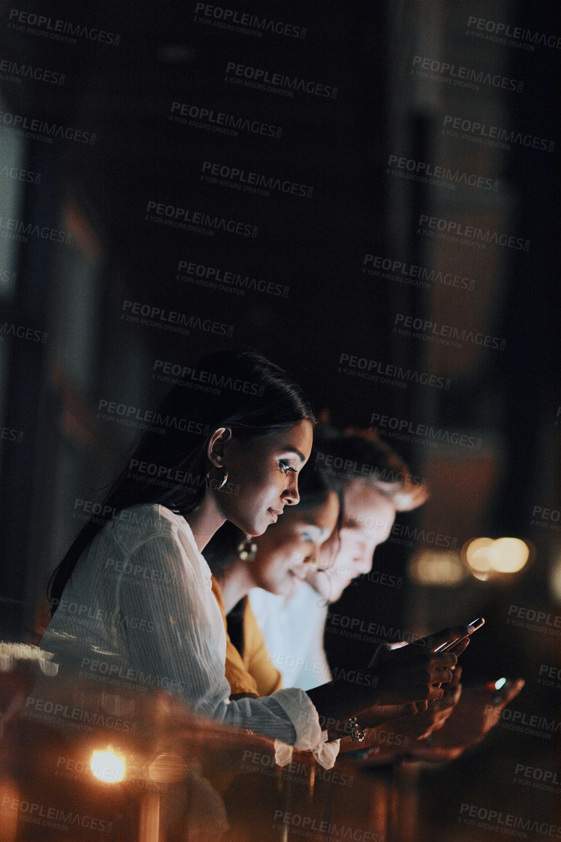 Buy stock photo Shot of a group of businesspeople using digital devices outside an office at night
