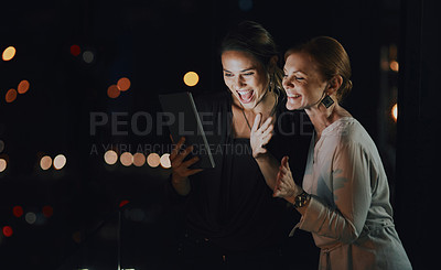 Buy stock photo Shot of two businesswomen using a digital tablet to make a video call outside an office at night