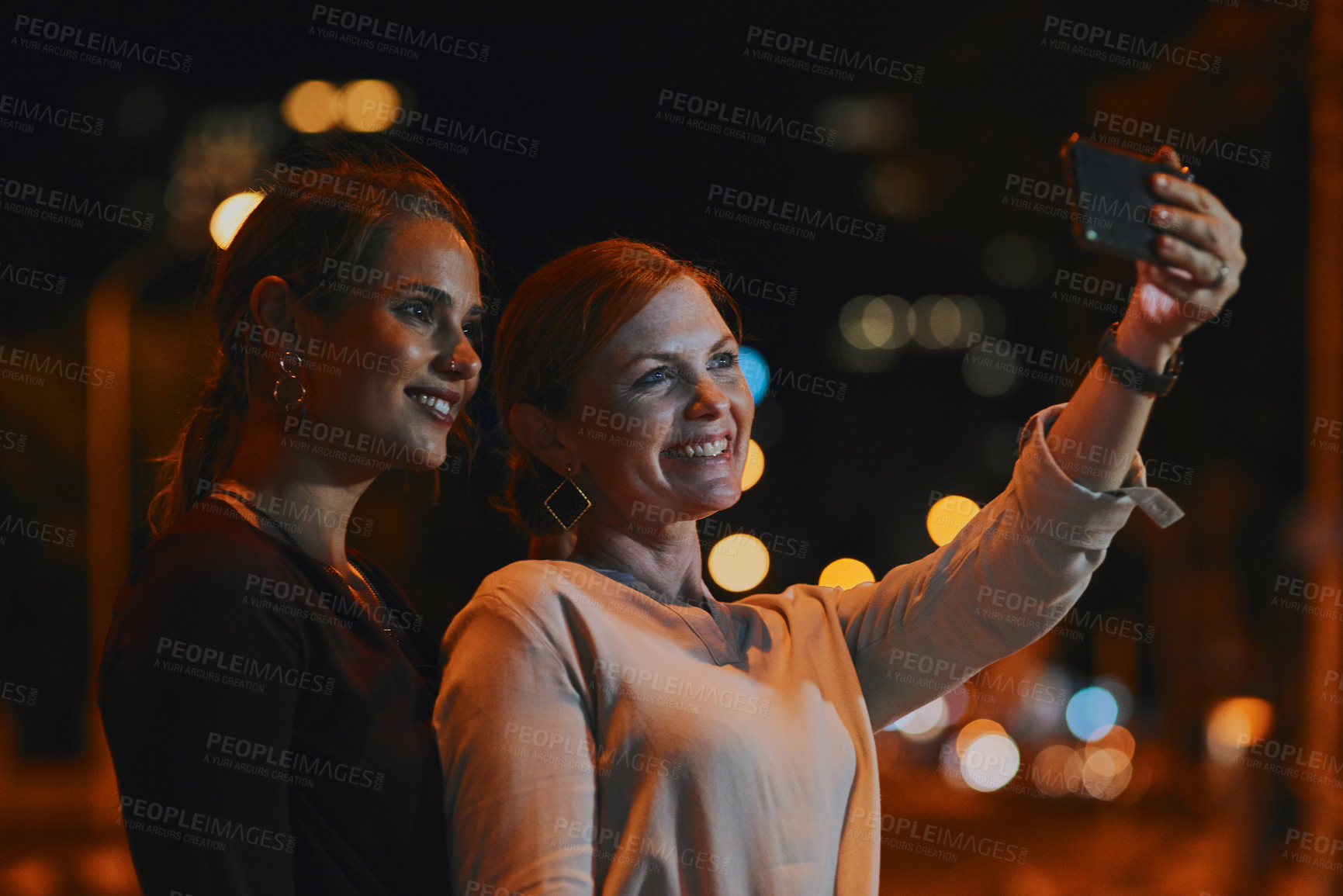 Buy stock photo Shot of two businesswomen taking selfies together outside an office at night