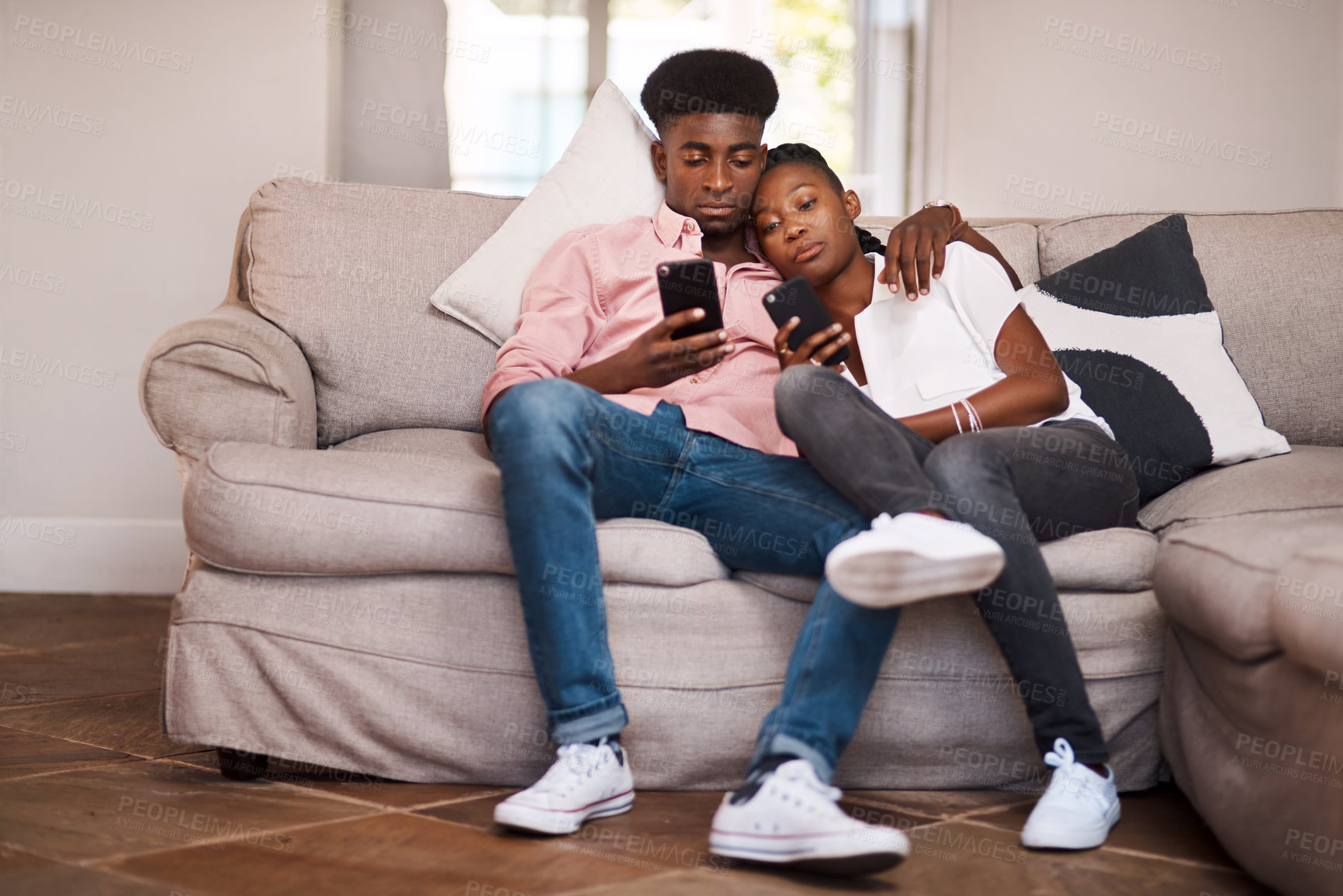 Buy stock photo Shot of a couple using their cellphones while relaxing on the sofa at home