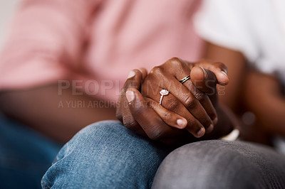 Buy stock photo Cropped shot of an unrecognizable couple holding hands while sitting together