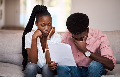Buy stock photo Shot of a young couple looking stressed while going over paperwork at home