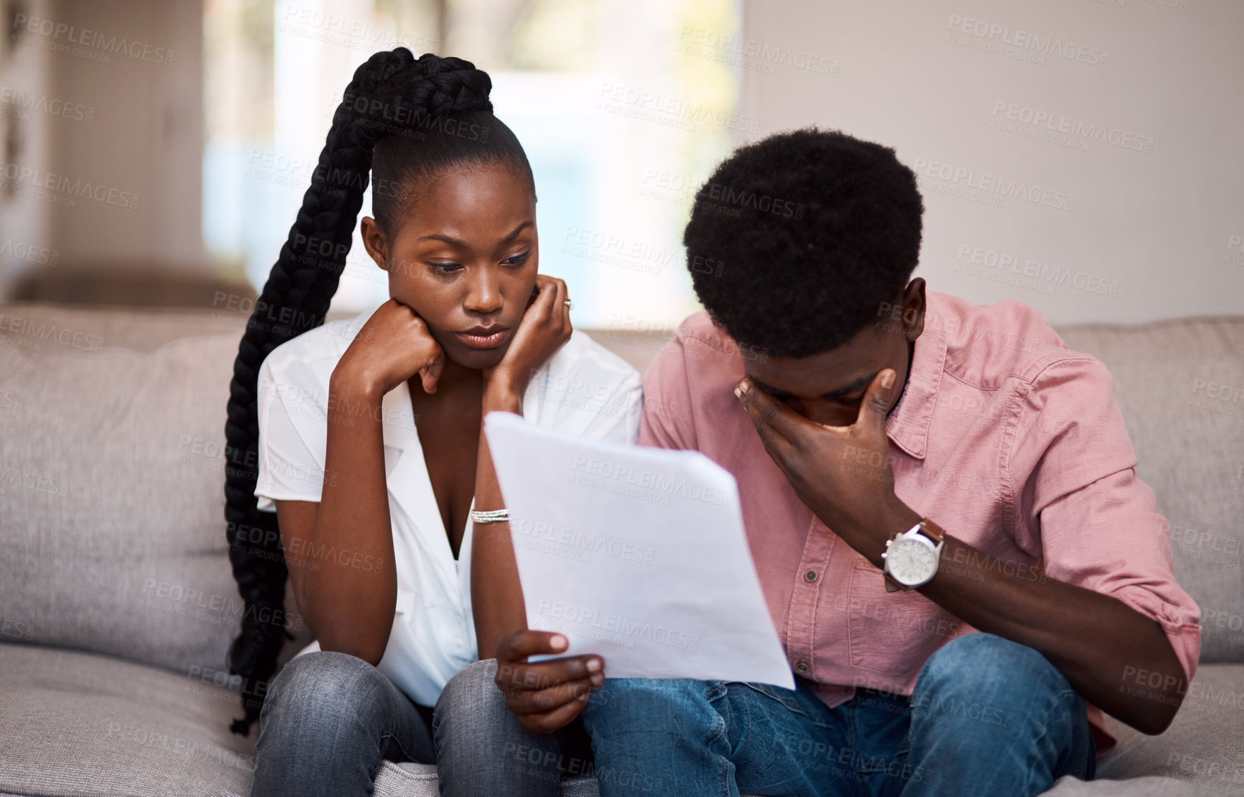 Buy stock photo Shot of a young couple looking stressed while going over paperwork at home