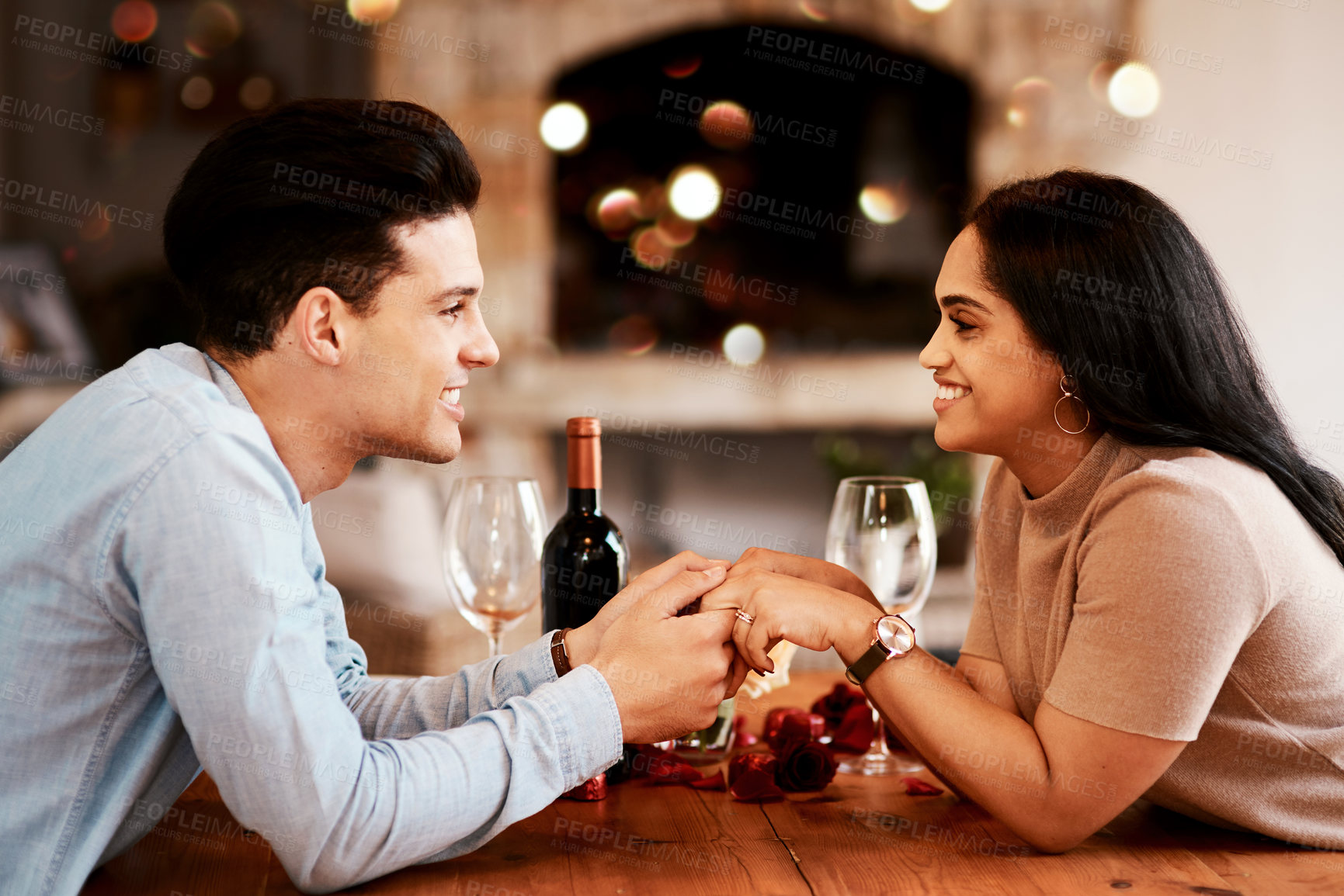 Buy stock photo Love, romance and couple holding hands at table on valentines day date at home with smile and bokeh. Date night, man and woman in living room, valentine celebration and happy relationship together.