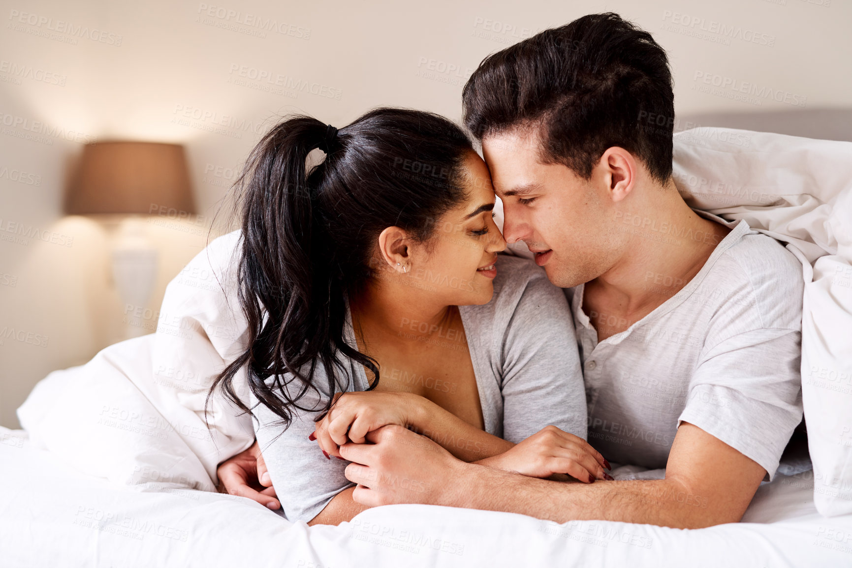 Buy stock photo Love, bed and morning with a diversity couple in the bedroom of their home together for romance or intimacy. Sensual, foreplay or passion with a young man and woman in a house for romantic bonding