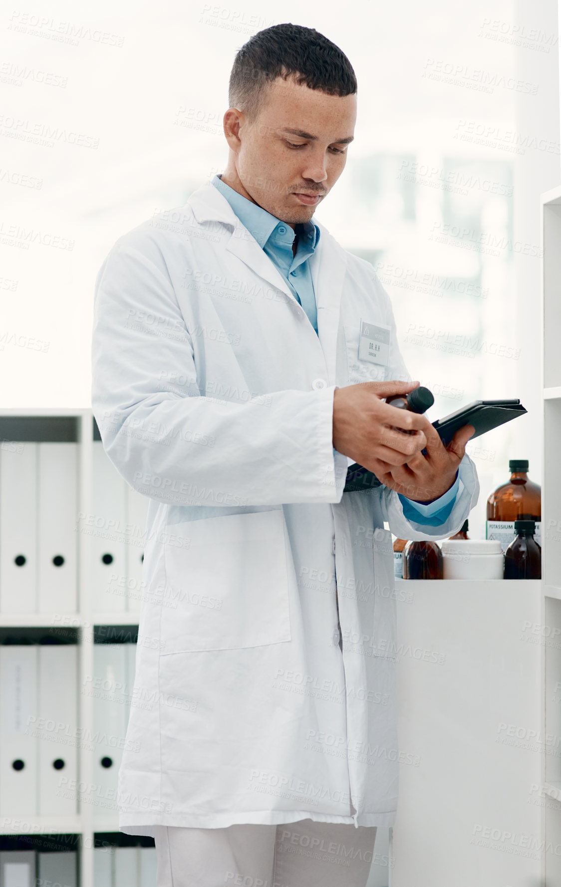 Buy stock photo Shot of a young scientist using a digital tablet while analysing medication in a laboratory