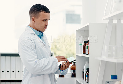 Buy stock photo Shot of a young scientist using a digital tablet while analysing medication in a laboratory