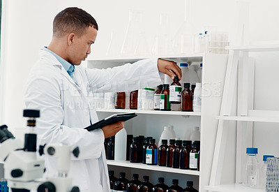 Buy stock photo Shot of a young scientist using a digital tablet while analysing medication in a laboratory