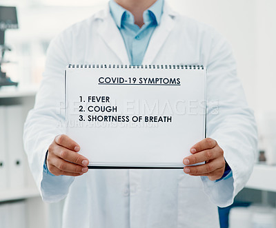 Buy stock photo Cropped shot of a scientist holding a sign with a list of COVID-19 symptoms on it in a modern laboratory