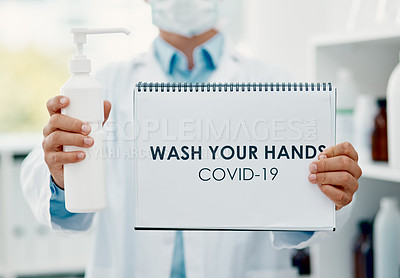 Buy stock photo Shot of a scientist holding a sign with “wash your hands” on it and hand sanitiser in a laboratory