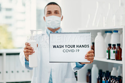 Buy stock photo Shot of a scientist holding a sign with “wash your hands” on it and hand sanitiser in a laboratory