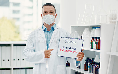 Buy stock photo Shot of a young scientist holding a sign with “We’ve got it under control” on it in a laboratory