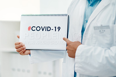 Buy stock photo Shot of a scientist holding a sign with “#COVID-19” on it in a modern laboratory