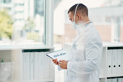 Buy stock photo Shot of a young scientist holding a notepad with “2019-nCov” on it in a modern laboratory