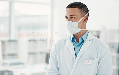 Buy stock photo Shot of a young scientist wearing a mask and looking thoughtful in a modern laboratory