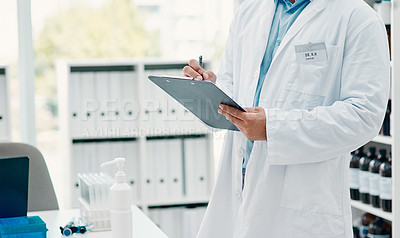 Buy stock photo Cropped shot of a scientist writing notes on a clipboard in a laboratory