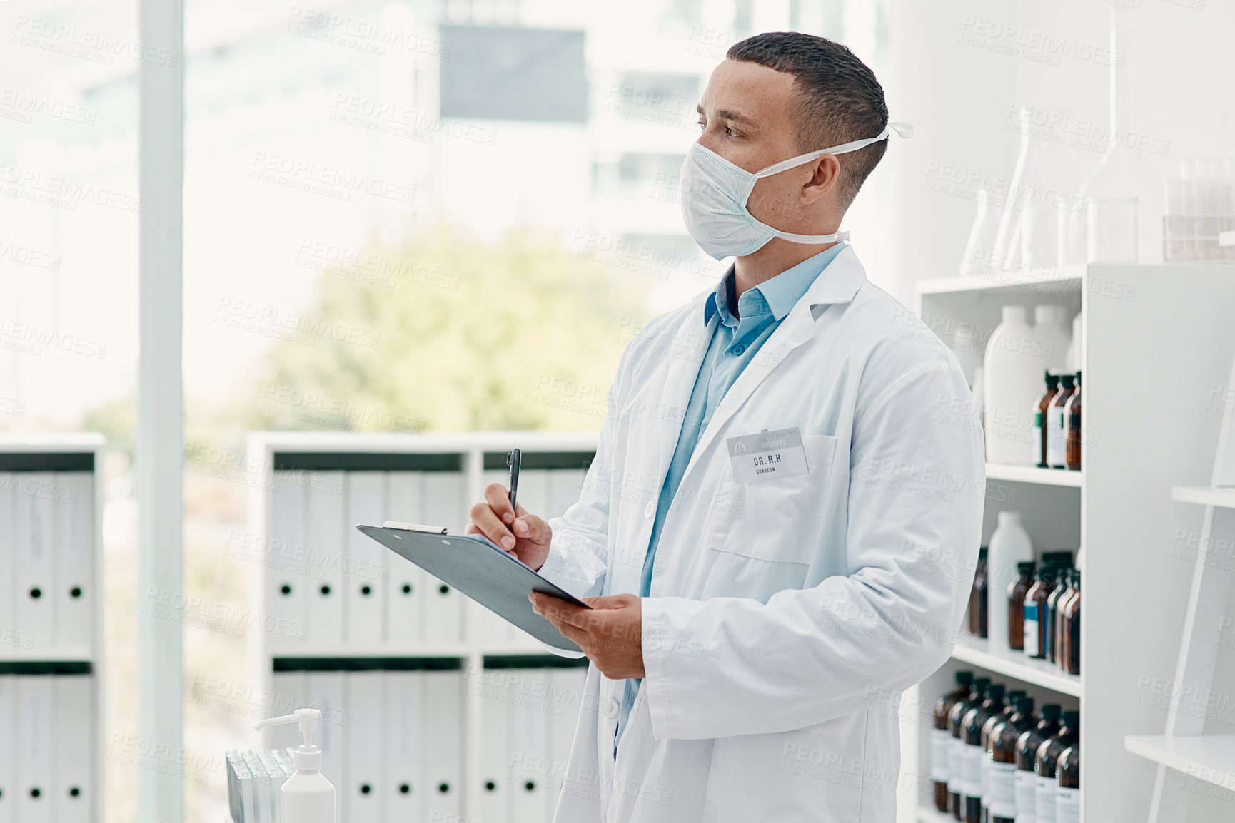 Buy stock photo Shot of a young scientist writing notes on a clipboard in a laboratory