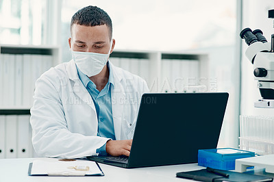 Buy stock photo Shot of a young scientist using a laptop while working on a coronavirus cure in a laboratory