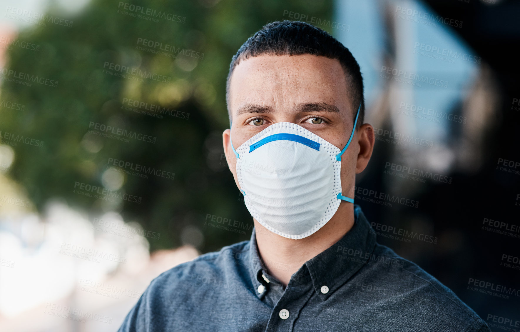 Buy stock photo Shot of a young businessman wearing a mask and standing on the balcony of an office