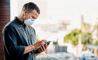 Buy stock photo Shot of a young businessman wearing a mask and using a smartphone on the balcony of an office