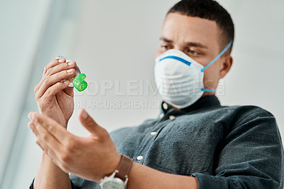 Buy stock photo Shot of a young businessman using hand sanitiser to disinfect his hands