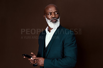 Buy stock photo Shot of a businessman using his cellphone against a brown background